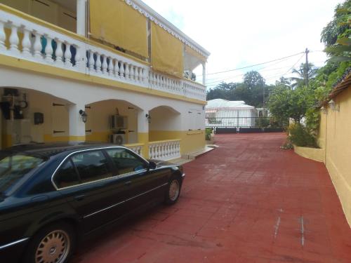 a black car parked next to a yellow building at Villa Mancina in Capesterre-Belle-Eau