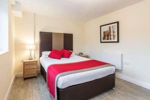 a bedroom with a large bed with red pillows at House of Fisher - Central Point in Basingstoke