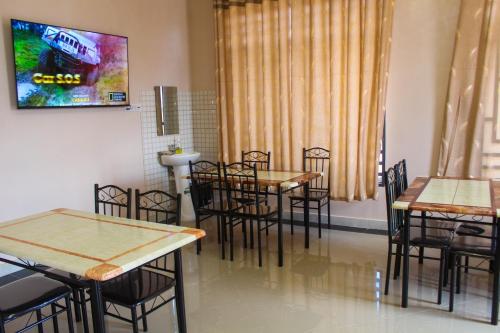 a dining room with tables and chairs and a television at Sajaca Lodge in Dodoma