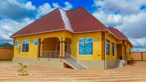 a small yellow house with a red roof at Sajaca Lodge in Dodoma