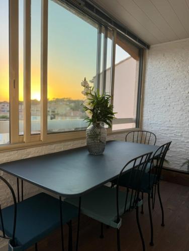 une table avec des chaises et un vase avec une plante dans l'établissement T2 parking privé, centre, plage et gare, à Les Playes