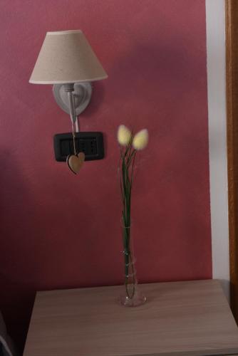 a lamp and a vase with flowers on a table at Casa Dante in Romano di Lombardia
