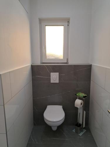 a bathroom with a toilet and a window at Ferienapartment "Zur Linde" in Breitenstein