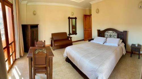 a bedroom with a bed and a chair and a table at Hotel Colonial Aguadas in Aguadas