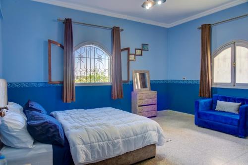 a blue bedroom with a bed and a blue chair at Dar Abaraz in Taroudant