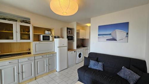 un salon avec un canapé et une cuisine dans l'établissement Première ligne mer ! T2 4 personnes, à La Peyrade