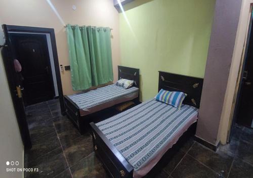 two beds in a room with green curtains at Al Qadir Residence in Multan
