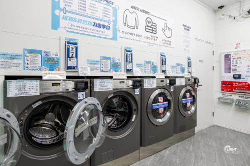 a laundry room with four washing machines and signs at Haeundae station 3min# seashore 3min# high floor view# luggage storage# flexible checkin& out# family in Busan