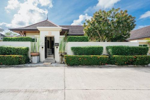 a house with a white fence and some bushes at Tranquil 3 Bedroom Garden Pool Villa in Laguna Phuket