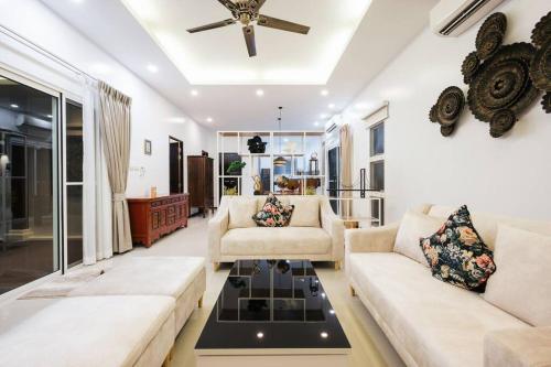 a living room with two couches and a ceiling fan at Tranquil 3 Bedroom Garden Pool Villa in Laguna Phuket
