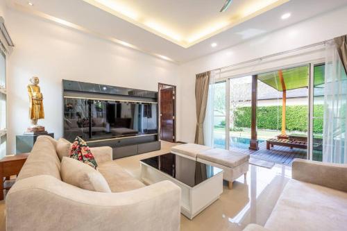 a living room with a couch and a table at Tranquil 3 Bedroom Garden Pool Villa in Laguna Phuket