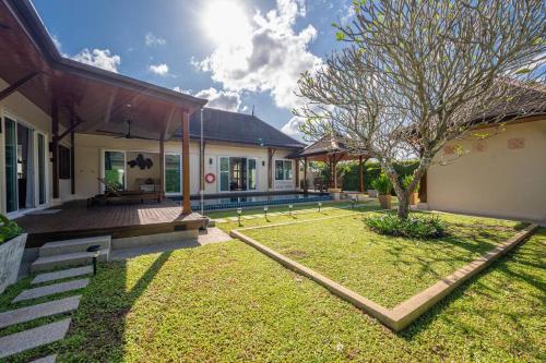 a backyard of a home with a tree in the yard at Tranquil 3 Bedroom Garden Pool Villa in Laguna Phuket