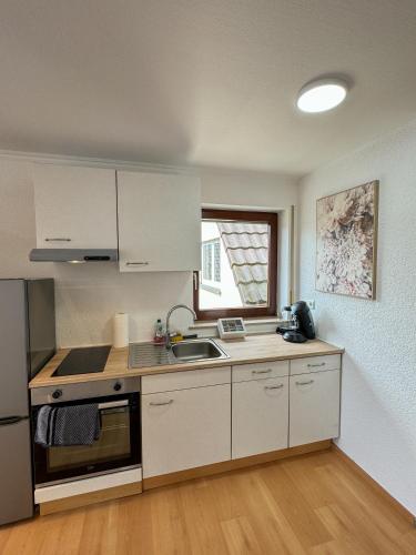 a kitchen with white cabinets and a sink at FeWo Central Rust in Rust