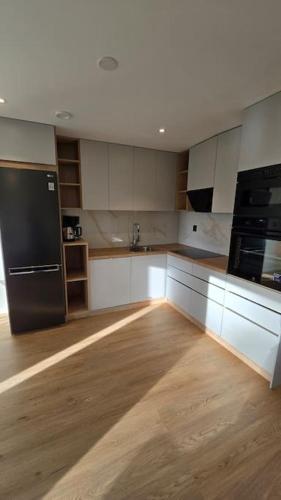 a kitchen with white cabinets and a black refrigerator at Nybyggd lägenhet i Vimmerby in Vimmerby