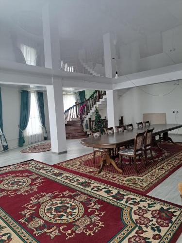 a large room with a table and chairs and a rug at Hostel Erkin in Karakol