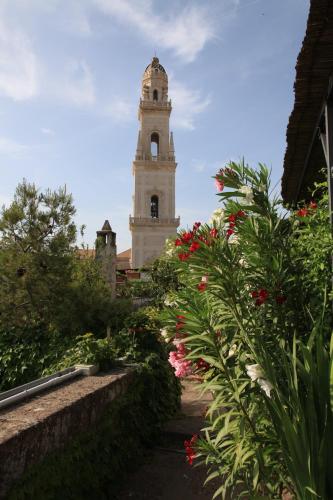 a clock tower in the background of a garden with flowers at Palazzo Rollo in Lecce