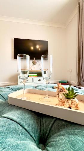 a tray with two wine glasses on top of a bed at Stylish quaint home hosted by ESONGRACE Stays in Stoke-on-Trent - Perfect for Families - Contractors - Holiday makers - Emergency Housing - Professionals in Stoke on Trent