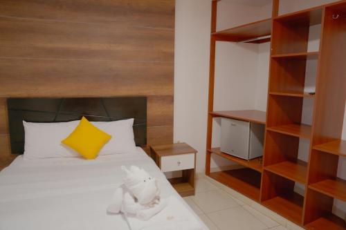 a bedroom with a bed with a yellow pillow and shelves at Hotel San Martín in San Juan de Marcona