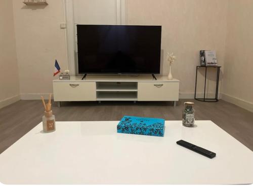 - un salon avec une télévision et une table blanche dans l'établissement Maison, au Mans