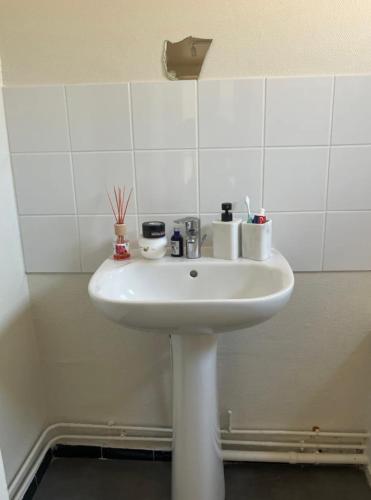 La salle de bains est pourvue d'un lavabo blanc et de carrelage blanc. dans l'établissement Maison, au Mans