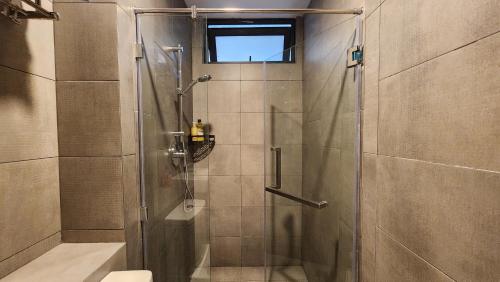 a shower with a glass door in a bathroom at K-Avenue with PS5 and Pool View by JH Project in Kampong Tangihan