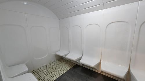 a bathroom with white walls and white urinals at K-Avenue with PS5 and Pool View by JH Project in Kampong Tangihan