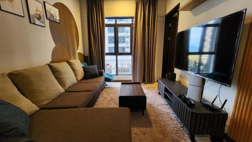 a living room with a couch and a flat screen tv at K-Avenue with PS5 and Pool View by JH Project in Kampong Tangihan