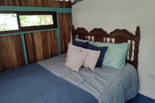 a bed with blue and white pillows in a room at Habitación rodeada de las copas de los árboles in San Ramón