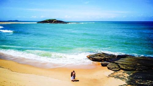 a woman standing on a beach near the ocean at Pousada Bem Te Vi in Guarapari