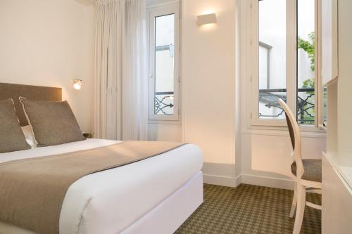 Una habitación de hotel con una cama y dos ventanas. en Hôtel Mistral, en París