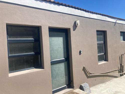 ein Gebäude mit zwei Fenstern mit Jalousien darauf in der Unterkunft Cottage on 36 Neethlingshof in Kapstadt