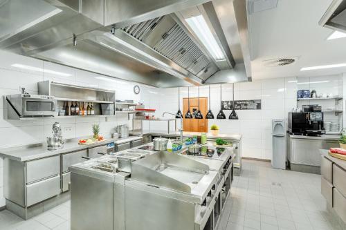 a large commercial kitchen with stainless steel appliances at Hotel Restaurant Zur Neroburg in Neroth