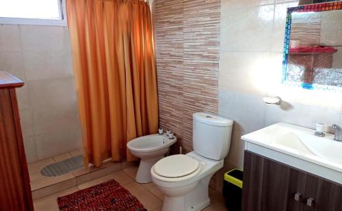ein Badezimmer mit Toilette und orangefarbenem Duschvorhang in der Unterkunft Luminosa casa en El Volcán in El Volcán