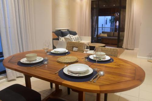 a wooden table with plates and glasses on it in a living room at Blue Waves Beachfront Penthouse in Flic-en-Flac