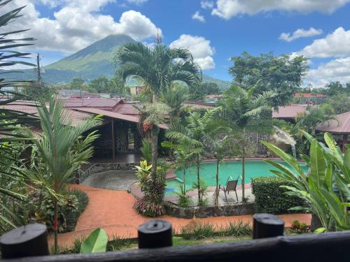 a resort with a pool and a mountain in the background at Hotel Iris Arenal in Fortuna