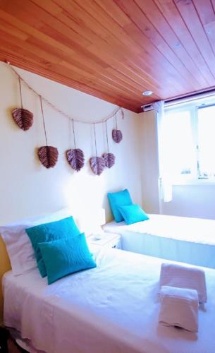 a bedroom with two beds and a wooden ceiling at Casa do Portão Azul - Dourada in Atouguia da Baleia