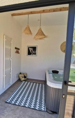 - une baignoire dans une chambre dotée d'un tapis bleu et blanc dans l'établissement Gîte Histoire de Miel, à Verzeille