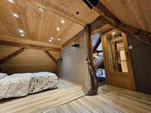 une chambre avec un lit dans une pièce avec des plafonds en bois dans l'établissement Les Hauteurs de Ranspach, à Ranspach