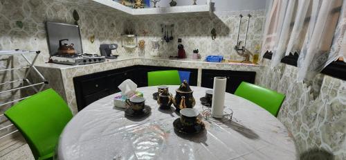 a kitchen with a round table with green chairs at Appartement Riad 5min à pied de l'aéroport in Marrakech