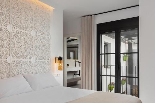 Un dormitorio con una cama blanca y una ventana. en Casa Azalia - Marbella Old Town, en Marbella