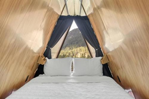 a bed in a tent with a large window at Pines Cabin- A-Frame- Hot Tub-Sauna- Firepit in Woodville