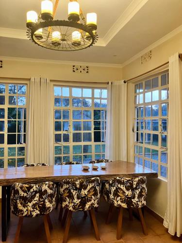 a dining room with a large table and windows at Allamanda House Meru in Arusha
