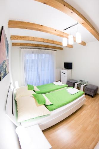 a bedroom with a large bed with green sheets at Penzión Tri Koruny in Spišská Stará Ves