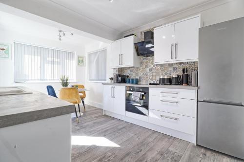 a kitchen with white cabinets and a counter top at Rayleigh Weir - Luxury 3 bedroom house with games room in Rayleigh