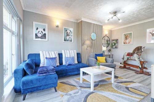 a living room with a blue couch and a table at Rayleigh Weir - Luxury 3 bedroom house with games room in Rayleigh