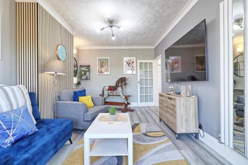 a living room with a blue couch and a table at Rayleigh Weir - Luxury 3 bedroom house with games room in Rayleigh