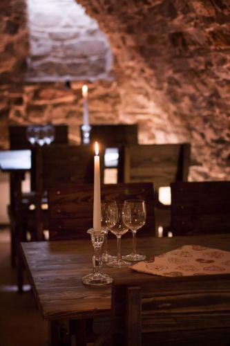 a candle and wine glasses on a wooden table at Penzión Tri Koruny in Spišská Stará Ves