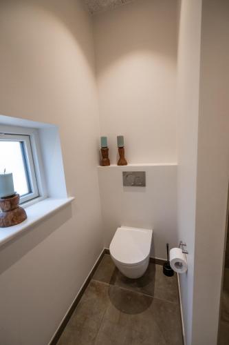 a white bathroom with a toilet and a window at Sdr. Omme Bed & Breakfast in Sønder Omme