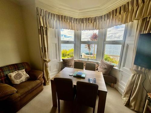 a living room with a table and a large window at Bayside - Breathtaking views of the Clyde in Rothesay