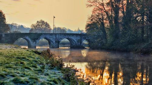 a bridge over a river with trees and water at Mon Petit Cottage - B&B and Guest House in Bunclody in Bunclody